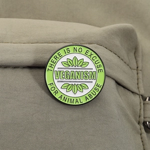 Detail of round veganism enamel pin with animal rights slogan on canvas fabric