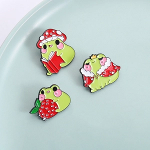 Three cute green frog enamel pins featuring mushroom hat, royal crown, and strawberry