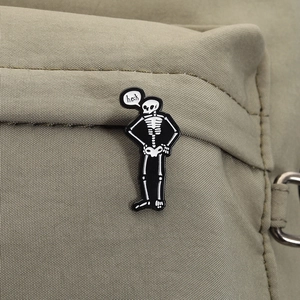 Dettaglio della spilla smaltata con scheletro divertente su borsa con fumetto heck