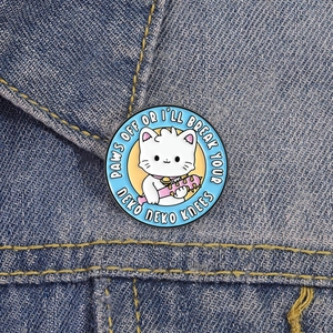 Détail du badge en émail chat mignon avec une masse sur une veste en denim bleu