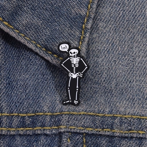 Dettaglio della divertente spilla smaltata a teschio con nuvoletta 'heck' su denim