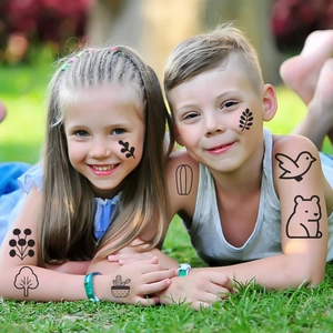 Bambini con tatuaggi temporanei di alberi e orsi su un prato verde in una giornata di sole