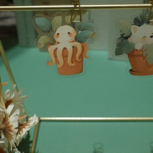 Macro view of cute cartoon octopus and cat stickers on a plant pot with gold clips