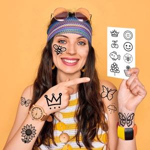 Primo piano di tatuaggi temporanei neri minimalisti con corone e fiori sulla pelle