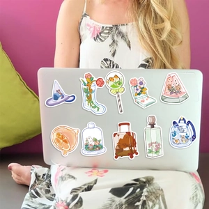 Close-up of cute cartoon stickers including magic hats and cats on a silver laptop lid