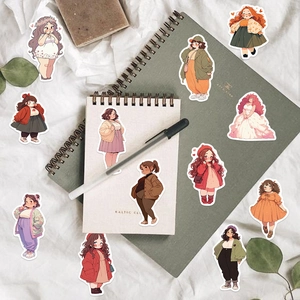Flat lay of cute cartoon girl stickers scattered on a notebook with artistic stationery props
