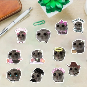 Sad Hamster meme stickers displayed on wood with pens and office stationery