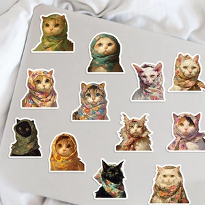 Primer plano de pegatinas de gatos con pañuelos florales sobre un portátil