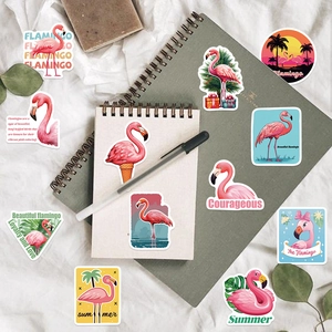 Flat lay of pink flamingo decals and tropical stickers on a notebook and fabric