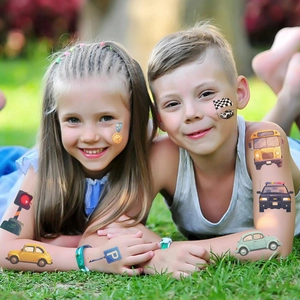 Enfants sur l'herbe avec des tatouages temporaires de voitures et bus de dessin animé