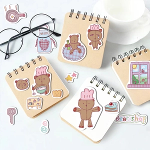 Detail of cute bear cartoon stickers on a spiral notebook with eyeglasses and ceramic cup