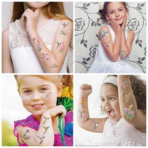 Dettaglio di tatuaggi temporanei colorati con uccelli e fiori sulla pelle dei bambini