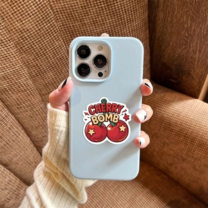 Gros plan sur une coque bleu clair avec motif Cherry Bomb tenue dans un cadre cosy