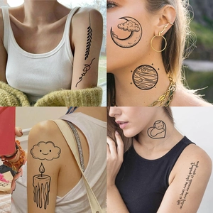 Close-up of black linear temporary tattoos with moon, stars, and lettering on skin