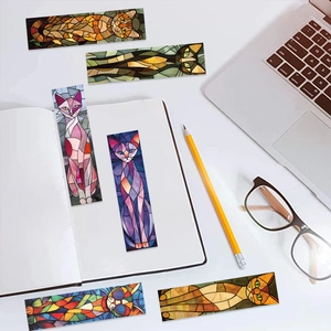 Close-up of artistic stained glass style cat bookmarks on a modern office desk setup