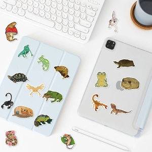 Close-up of waterproof cartoon reptile stickers applied to a white laptop and tablet case