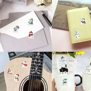Christmas snowman stickers applied on envelopes, notebooks, guitars, and coffee mugs