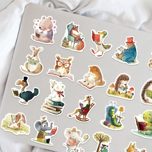 Detail showing cartoon animals reading stickers applied on a grey laptop cover surface