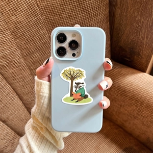 Detail of light blue phone case with cartoon animal reading sticker in cozy home setting