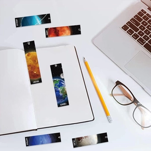 Flat lay of artistic planetary bookmarks on a desk with glasses and a laptop