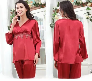 Detailed view of red satin pajamas with delicate lace embroidery and glossy texture