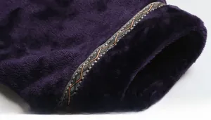 Close-up of deep purple flannel bathrobe cuff with geometric embroidered lace trim