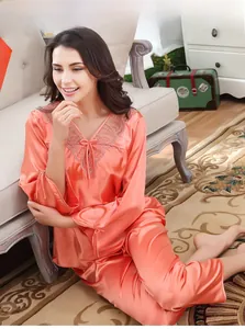 Dettaglio del pigiama in seta arancione con scollo a V in pizzo e fiocchi decorativi