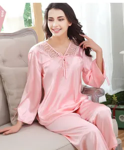 Pigiama in seta rosa con pizzo sullo scollo a V e maniche lunghe sul divano