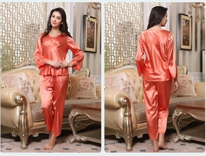 Front and back view of coral silk satin long-sleeve women's pajama set in a living room