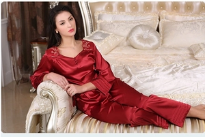 Détail d'un pyjama en soie rouge avec broderie florale et finitions volantées