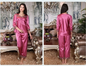 Detail of silk-like long sleeve pajamas with intricate purple lace trim and bow accent