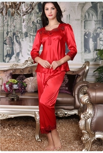 Detail of red silk pajamas featuring intricate lace trim on cuffs and a soft satin finish