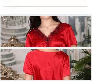 Détail du pyjama en satin rouge montrant le col en V avec broderie florale en dentelle