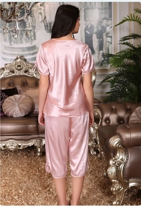 Détail du pyjama en satin rose avec nœuds aux poignets et texture soyeuse en gros plan