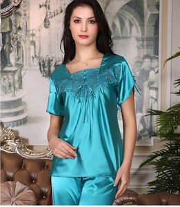 Detail of teal silk pajama set with intricate lace embroidery and satin ribbon ties