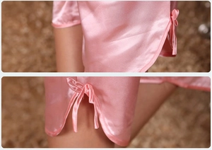 Détail du pyjama en satin rose montrant la fente latérale avec un élégant nœud décoratif en soie