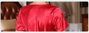 Detail of red silk sleepwear featuring smooth satin texture and bow design on the sleeves