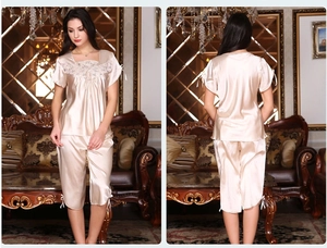 Detail of silk-like champagne pajama set with white lace neckline and bow accents