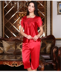 Close-up of red satin sleepwear showing intricate lace embroidery and neckline bow detail