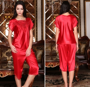 Detail of red satin pajamas with lace embroidery and drawstring bows on sleeves and hem
