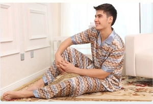 Detail of men's satin pajama set featuring blue geometric wave patterns and silk texture