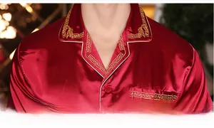 Close-up of red silk pajamas featuring luxury gold Greek key embroidery on lapel