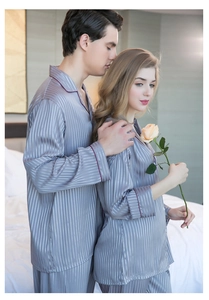 Detail of silk satin couple pajamas featuring vertical stripes and red piped trim accents