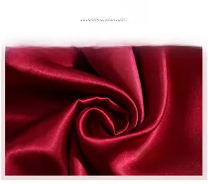 Detailed view of the dark red silk satin fabric texture and premium glossy sheen