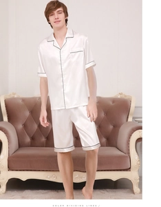 Close-up of pearl white silk pajama set with black piping and button-down detail