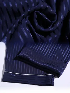 Detail of dark blue striped silk pajama fabric with white piping and smooth texture