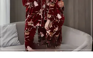 Dettaglio del pigiama in velluto rosso con stampa floreale vintage e profili bianchi sui polsi