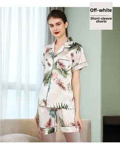 Détail de pyjama en soie blanc crème avec imprimé palmier tropical et liseré noir contrasté