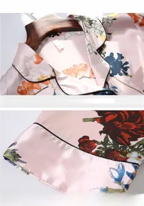 Détail du haut de pyjama en satin de soie rose à fleurs avec col à revers et passepoil noir
