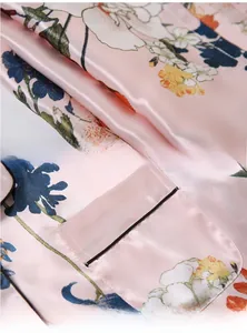 Gros plan sur le tissu satiné rose du pyjama avec imprimé floral et liseré noir sur poche